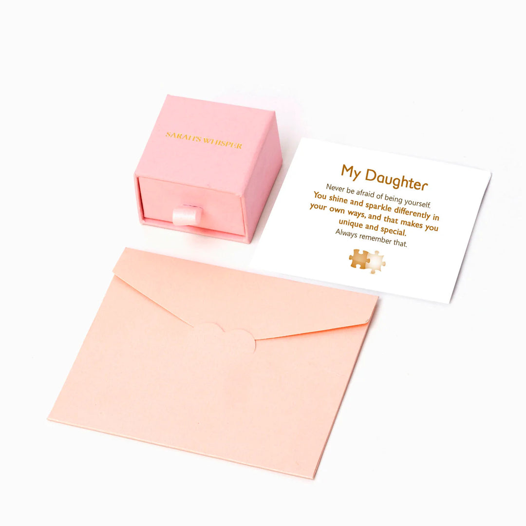 To My Daughter 'You Shine and Sparkle Differently' Puzzle Ring - A unique copper ring with a special gold-colored piece in the middle, symbolizing the distinctive and special nature of your daughter. This thoughtful gift comes with an inspiring greeting card, a gift box, and a gift bag, reminding her of her unique sparkle and individuality. Suitable for all ages