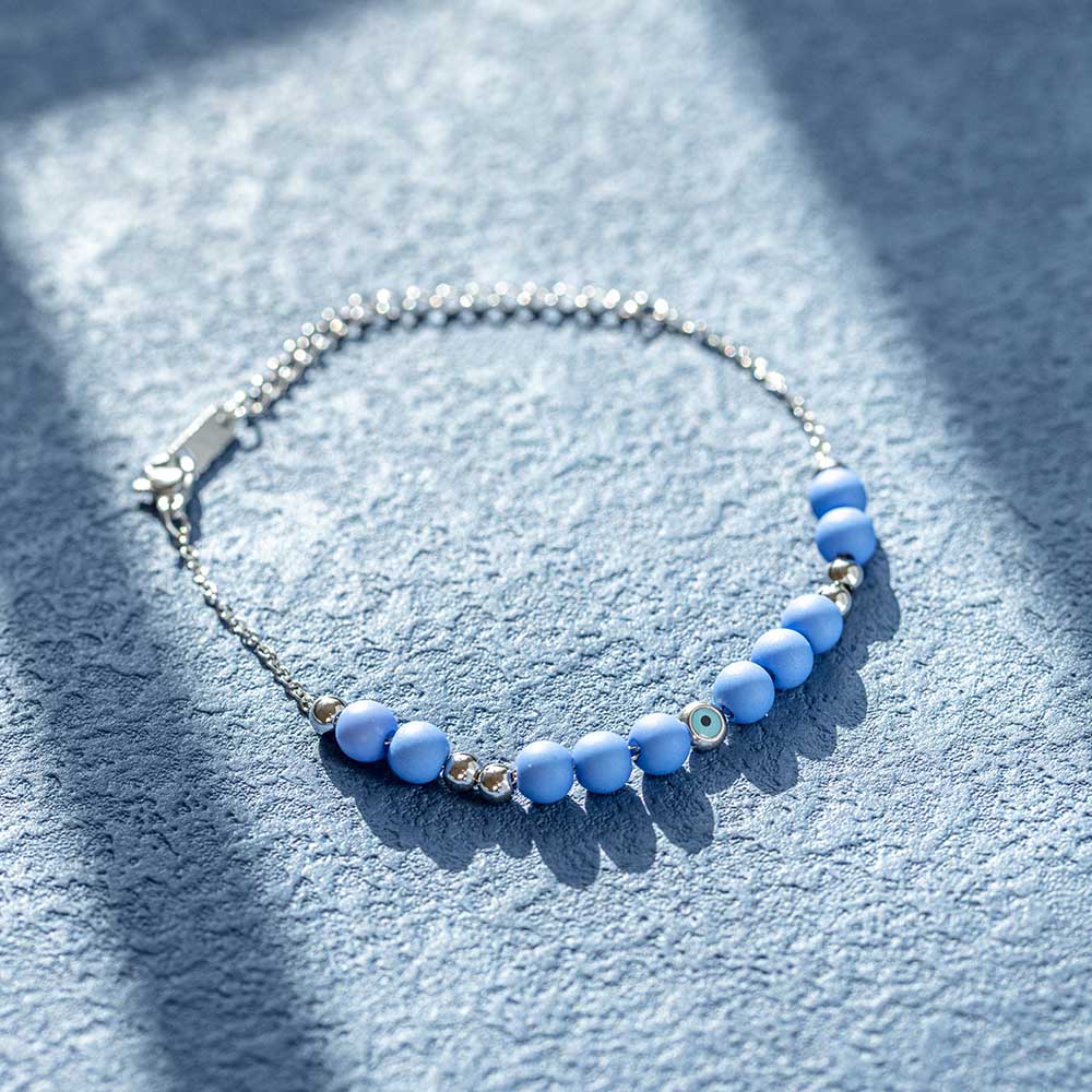 A titanium steel bracelet featuring an evil eye design, symbolizing protection from negativity and harm. Accompanied by a greeting card, gift box, and bag. Material: Titanium steel. Processing Techniques: Plating. Suitable for all ages.