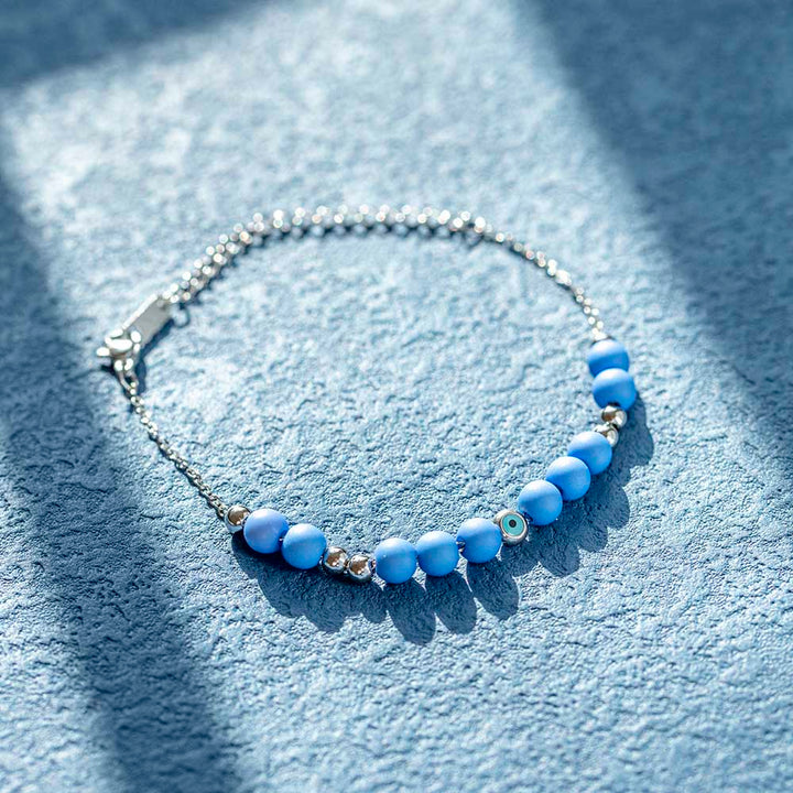 A titanium steel bracelet featuring an evil eye design, symbolizing protection from negativity and harm. Accompanied by a greeting card, gift box, and bag. Material: Titanium steel. Processing Techniques: Plating. Suitable for all ages.