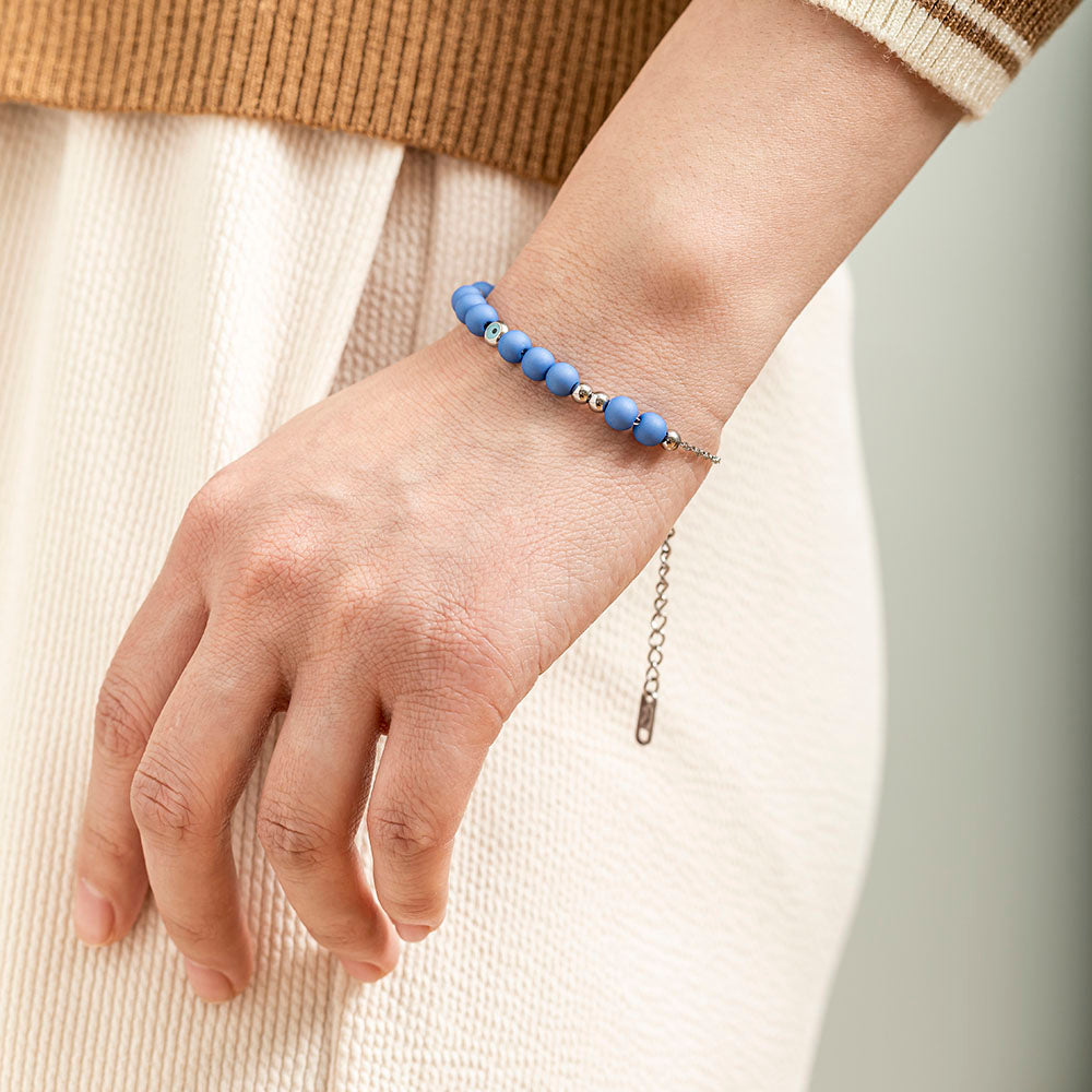 A titanium steel bracelet featuring an evil eye design, symbolizing protection from negativity and harm. Accompanied by a greeting card, gift box, and bag. Material: Titanium steel. Processing Techniques: Plating. Suitable for all ages.