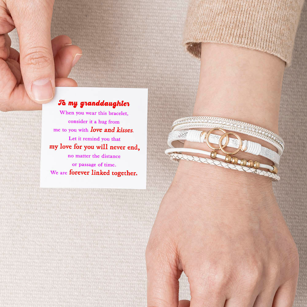 A close-up view of a leather bracelet with two interlocking rings at its center, representing the eternal bond between a granddaughter and a grandmother. The bracelet is accompanied by a greeting card and packaged in a gift box and bag. Material: Leather. Processing Techniques: Plating. Suitable for all ages."