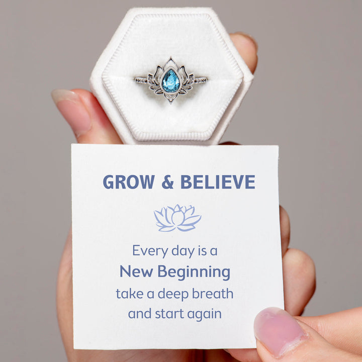 The image shows a silver ring with a lotus design, accompanied by a greeting card. The card reads "GROW & BELIEVE Every day is a New Beginning take a deep breath and start again." The ring is part of the "Every day is a New Beginning" set, made of S925 sterling silver with a zircon stone. It is suitable for all ages.
