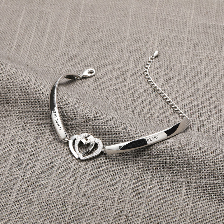 Double Heart Bracelet with intertwined rings, engraved with "Not sisters by blood but sisters by heart", symbolizing strong friendship bonds, made of copper with plating finish